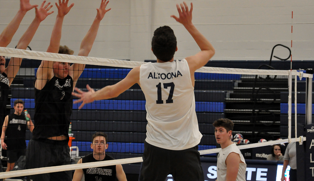 Photo (by Cory Maines): Freshman Ben Beaver goes up to hit the ball past a pair of Juniata blockers during Wednesday night's match in the Adler Arena.