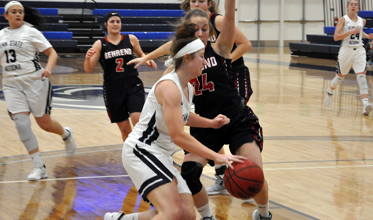 Photo (by Cory Maines): Junior guard/forward Kaley Strittmatter dribbles in front of Penn State Behrend's #24 Kourtney Beamesderfer during Thursday night's AMCC Tournament game.